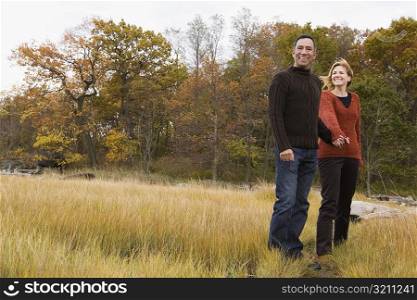 Mature couple standing on the grass with holding each other&acute;s hands