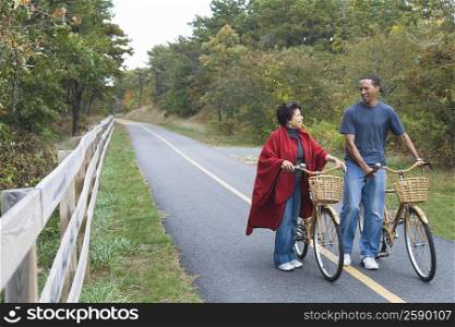 Mature couple standing on the road with their bicycles and smiling