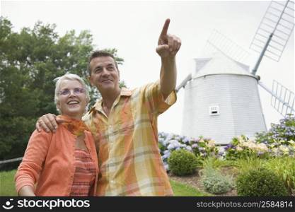 Mature couple standing together in front of a windmill in a park