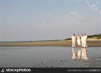 Mature couple standing with a mid adult woman and a mature man on the beach
