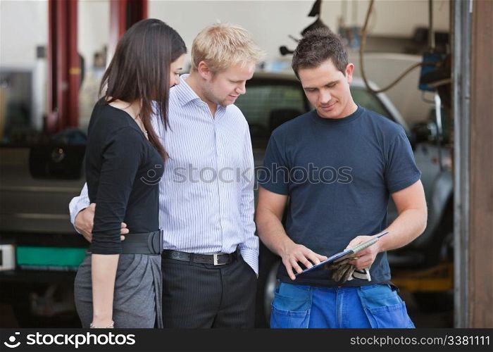 Mature couple standing with mechanic outside the garage