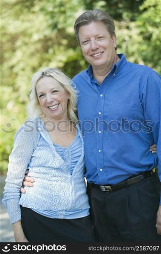 Mature couple standing with their arm around to each other and smiling