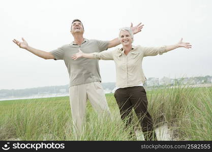 Mature couple standing with their arm outstretched in a grassy field