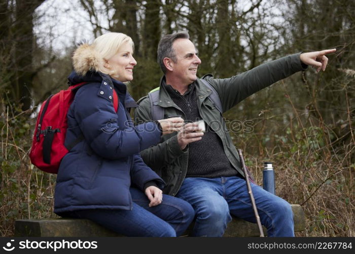 Mature Couple Stop For Rest And Hot Drink On Walk Through Fall Or Winter Countryside