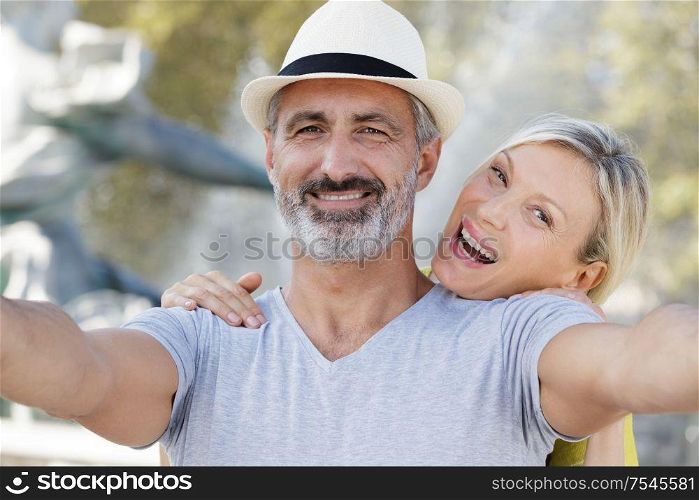 mature couple taking selfie outdoors with smart phone