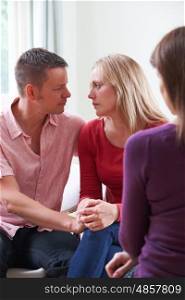 Mature Couple Talking With Counsellor As Man Comforts Woman