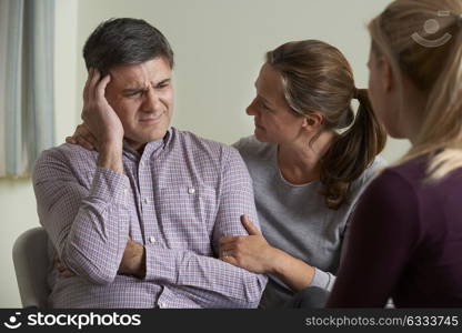 Mature Couple Talking With Counsellor As Woman Comforts Man