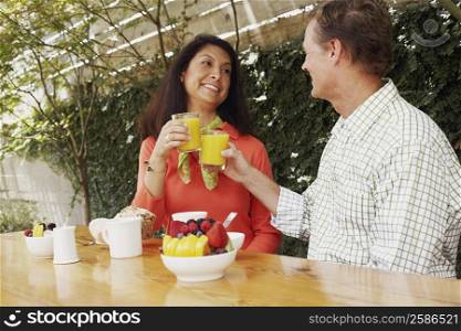 Mature couple toasting glasses of orange juice
