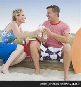 Mature couple toasting with water bottles and looking at each other