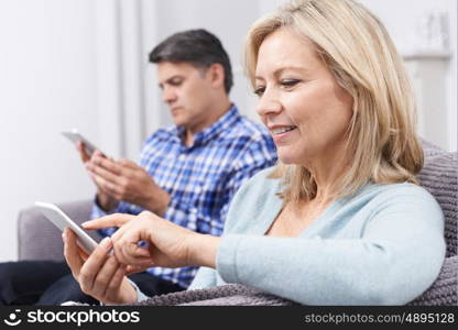 Mature Couple Using Digital Devices At Home