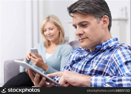 Mature Couple Using Digital Devices At Home