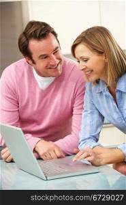 Mature couple using laptop in domestic kitchen