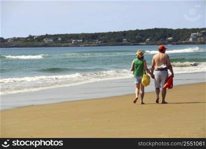 Mature couple walking on a sandy beach holding hands