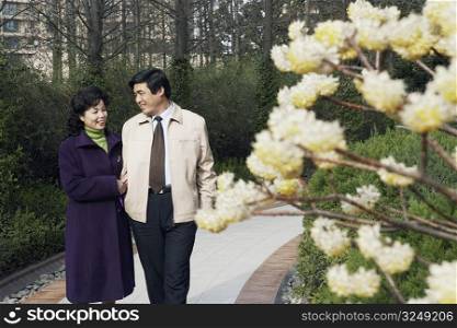 Mature couple walking together in a garden smiling