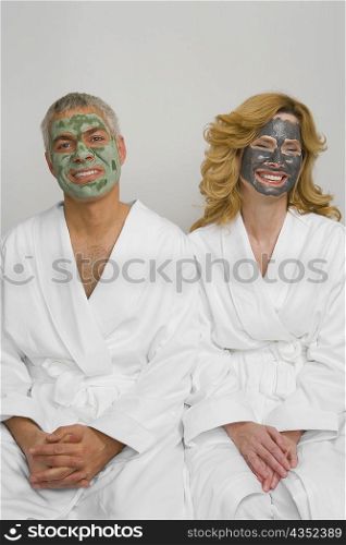Mature couple wearing facial masks and sitting together