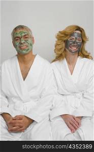 Mature couple wearing facial masks and sitting together