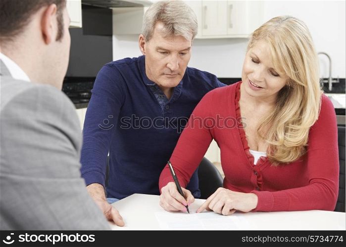 Mature Couple With Financial Advisor Signing Document At Home