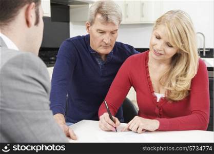 Mature Couple With Financial Advisor Signing Document At Home