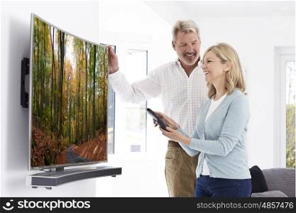 Mature Couple With New Curved Screen Television At Home