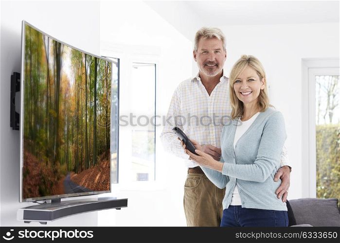 Mature Couple With New Curved Screen Television At Home