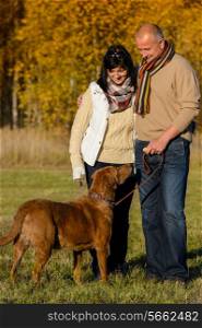 Mature couple with retriever dog embracing in autumn sunny park