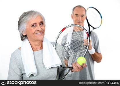 Mature couple with tennis racquets