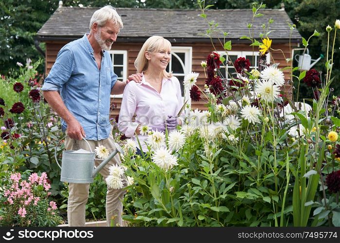 Mature Couple Working In Flower Beds In Garden At Home