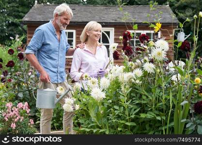 Mature Couple Working In Flower Beds In Garden At Home