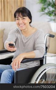 mature disabled woman in wheelchair watching movies at home