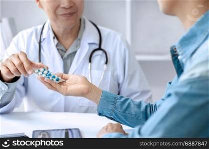 mature doctor giving pills to patient at a hospital / clinic