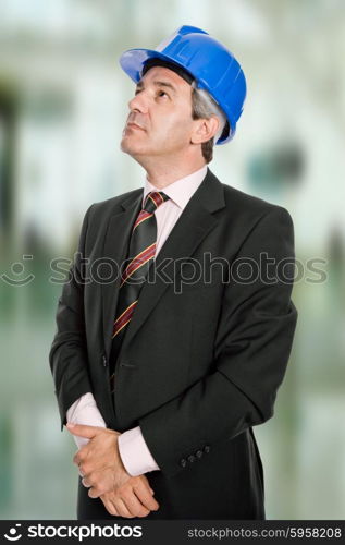 Mature engineer with blue hat looking up