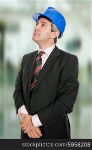 Mature engineer with blue hat looking up