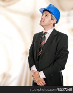 Mature engineer with blue hat looking up