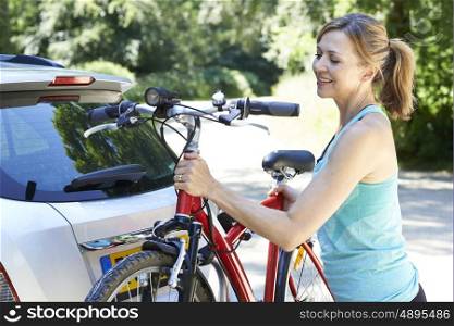 Mature Female Cyclist Taking Mountain Bike From Rack On Car