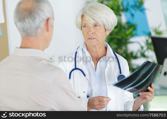 mature female doctor examining knee x-ray in clinic