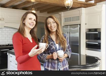 Mature Female Friends Standing In New Luxury Fitted Kitchen