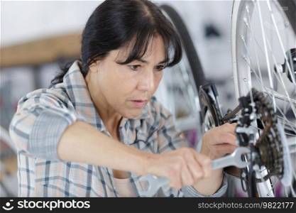 mature female mechanic repairing bicycle