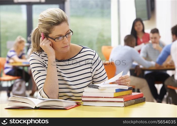 Mature Female Student Studying In Classroom With Books