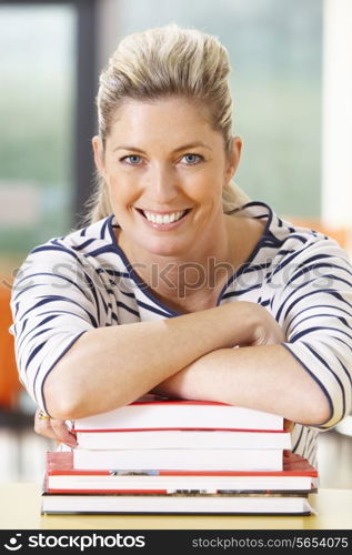 Mature Female Student Studying In Classroom With Books
