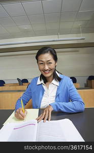 Mature female student working in lecture theatre, portrait