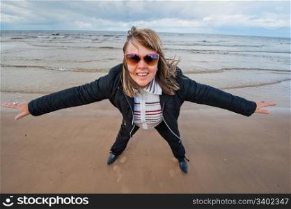 Mature funny attractive woman in sunglasses relaxing at the Baltic sea in autumn day.
