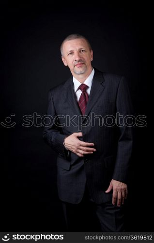 Mature handsome businessman holding hand on his black suit