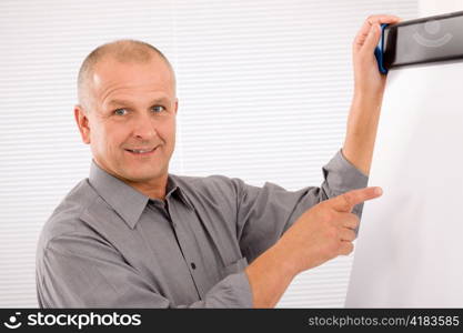 Mature handsome businessman pointing at empty flip chart looking aside