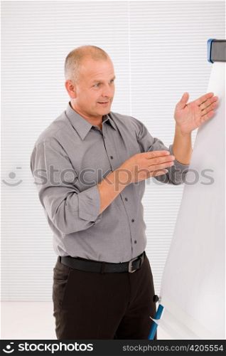 Mature handsome businessman pointing at empty flip chart looking aside