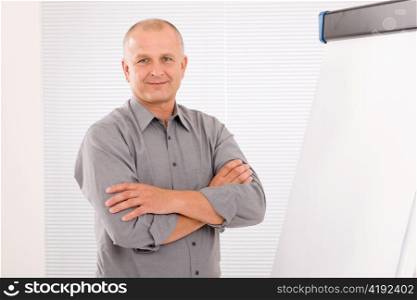 Mature handsome businessman standing in front of empty flip chart