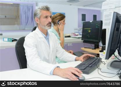 mature handsome doctor looking at exam results on the computer
