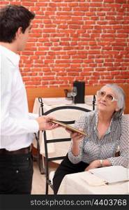 mature lady being served by waiter at restaurant