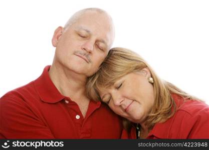 Mature loving couple cuddling with their eyes closed. White background.