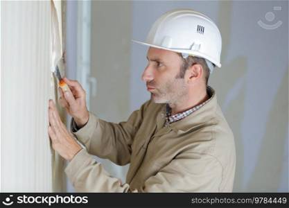 mature male builder stripping wallpaper with scraper
