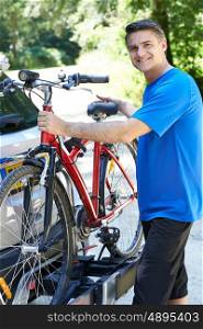 Mature Male Cyclist Taking Mountain Bike From Rack On Car